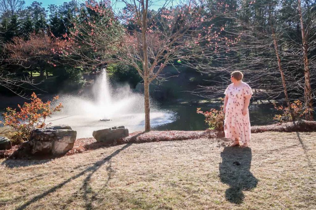 Lane Bryant Off The Shoulder Ruffled Maxi Dress in front of a pond with a fountain