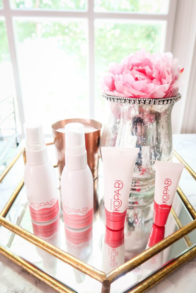 Kopari Beauty Products on Glass Table with Flowers